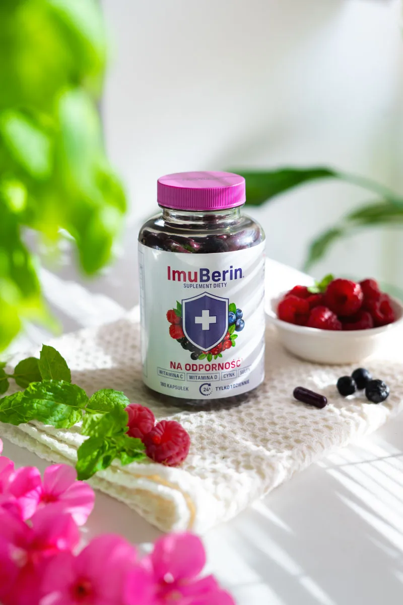 Natural Pharmaceuticals ImuBerin® Butelka kapsułek ImuBerin – suplement diety na odporność; na białym ręczniku obok malin, borówek i mięty, w jasnym świetle.