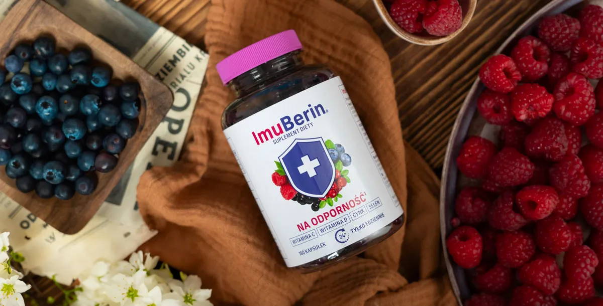 Natural Pharmaceuticals ImuBerin® Butelka suplementu ImuBerin „na odporność” z fioletową nakrętką na brązowej tkaninie; wokół świeże maliny i jagody na drewnianym blacie.